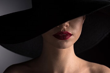 young-woman-in-black-hat-with-red-lips-on-black-stock-photograph_csp47739598